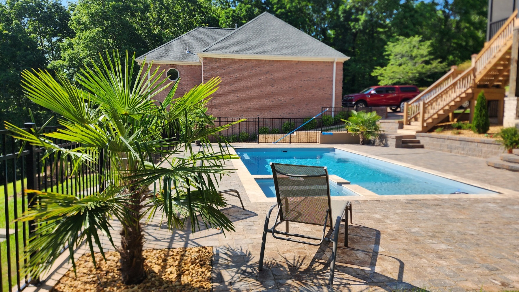 Backyard pool with palm tree and lounge chair.