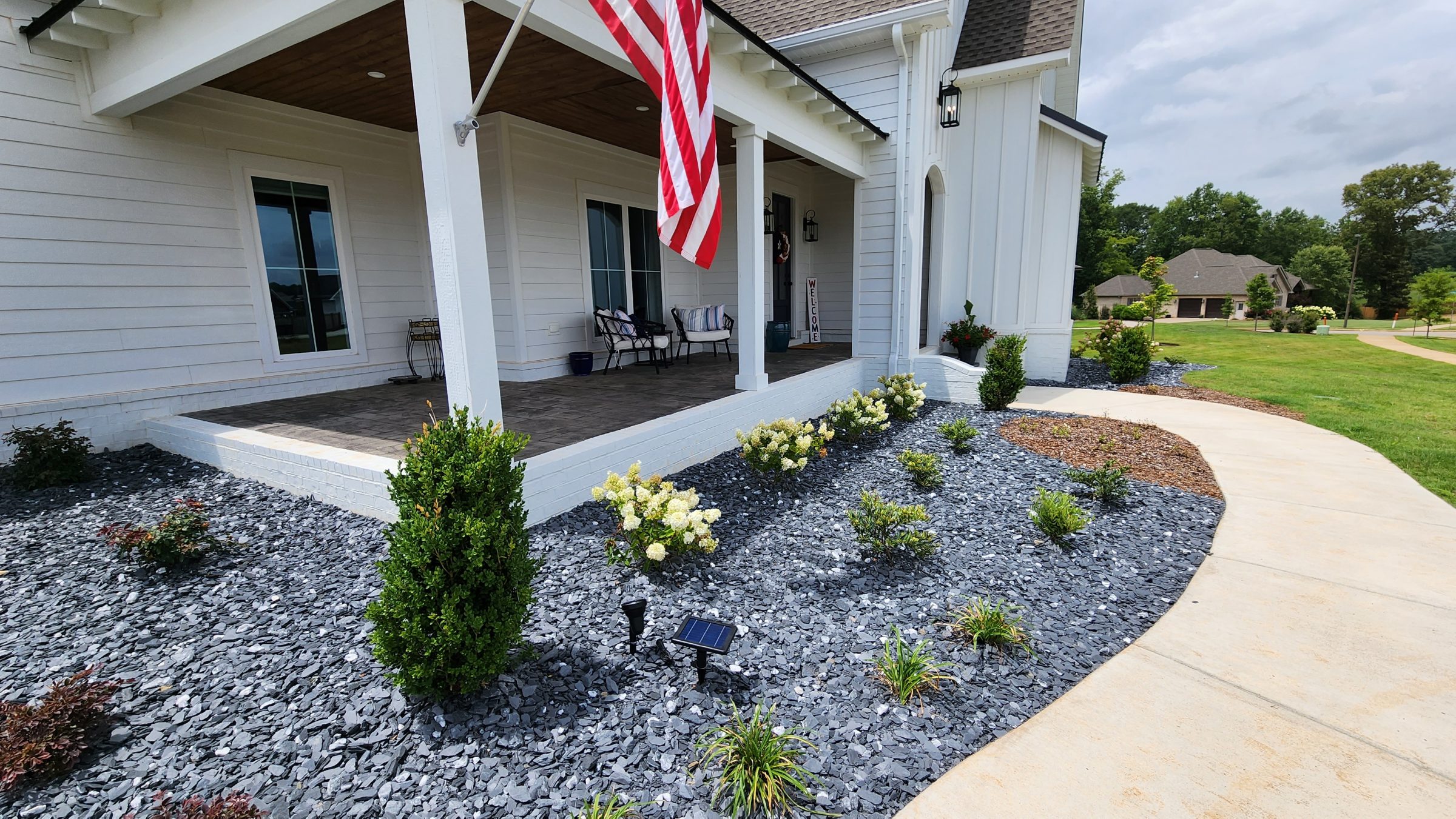 Front porch with American flag and garden