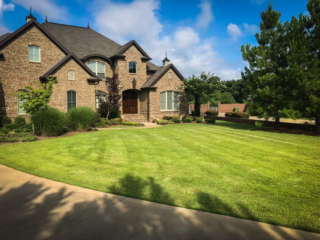 Brick house with manicured lawn and trees.