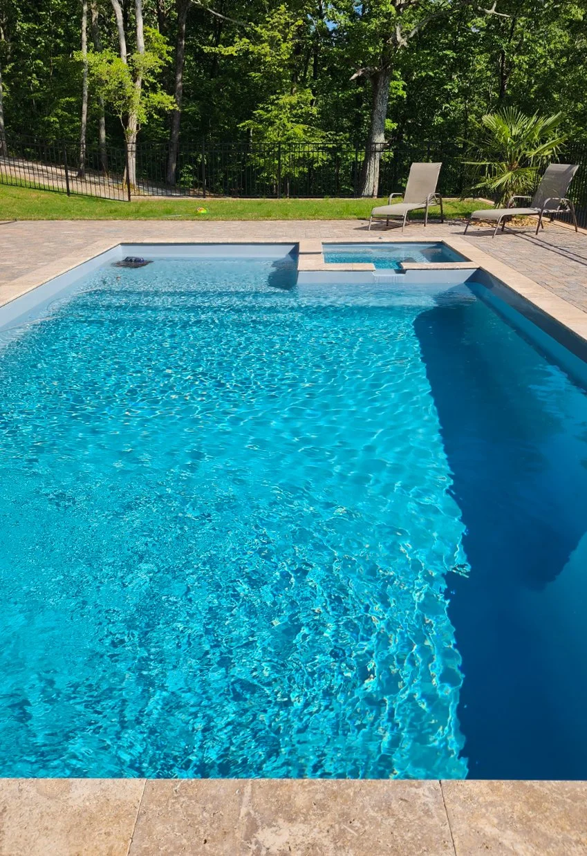 Blue swimming pool with chairs and trees