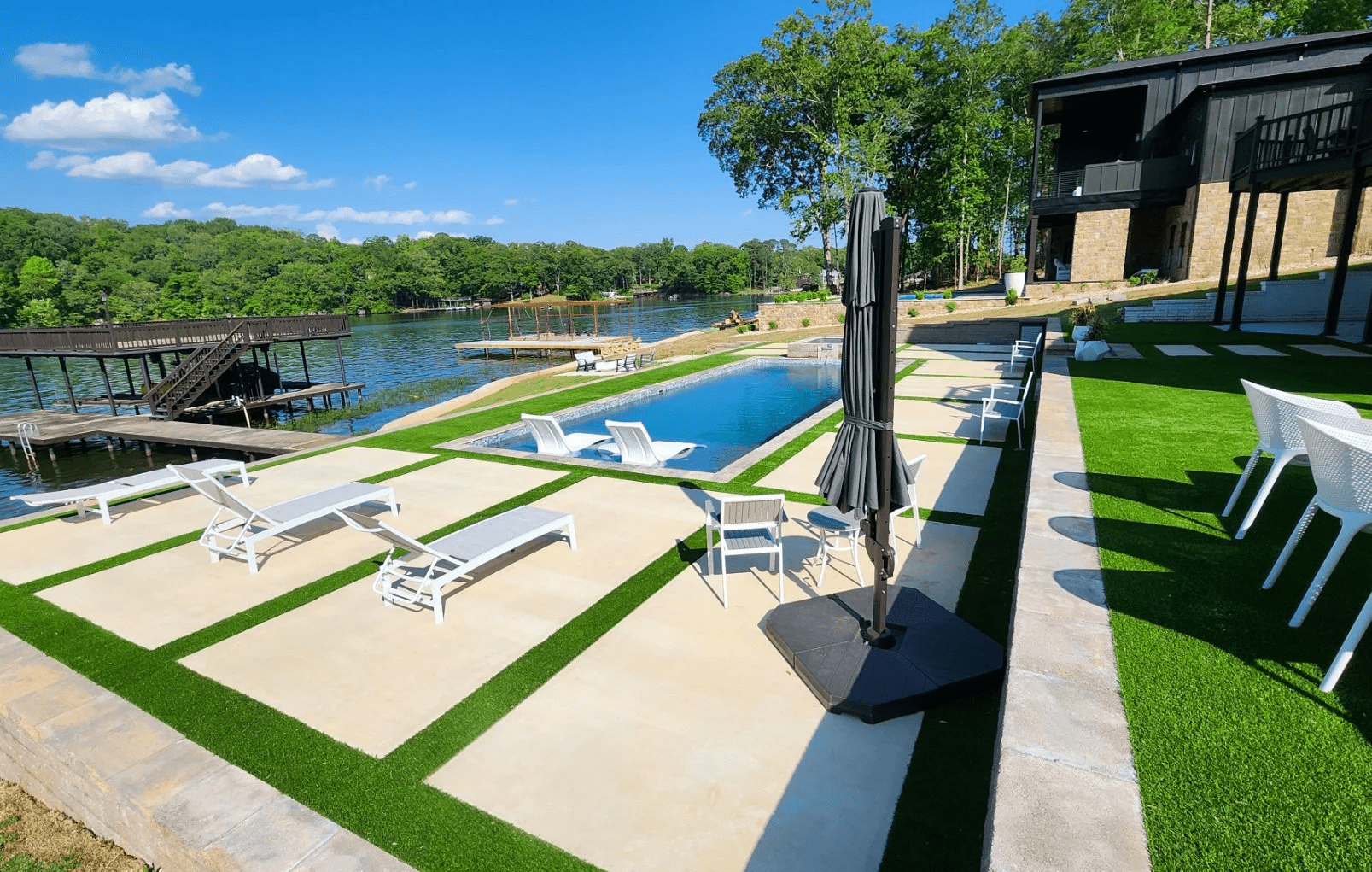 Lakeside pool with sun loungers and dock.