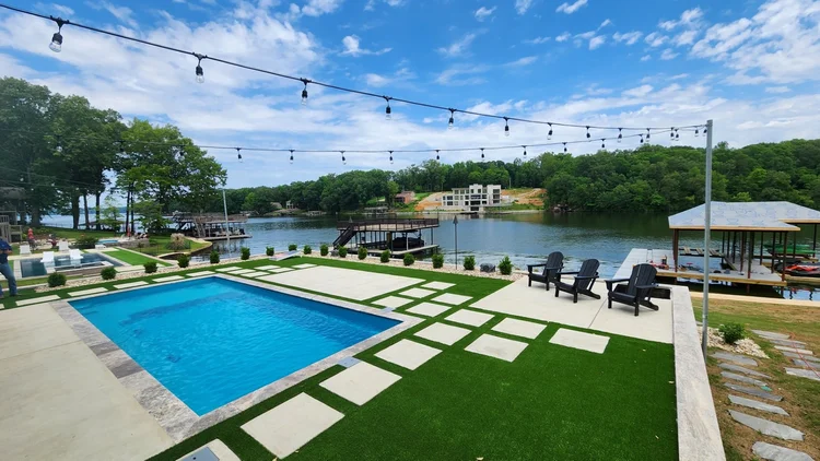 Lakeside pool with string lights and greenery