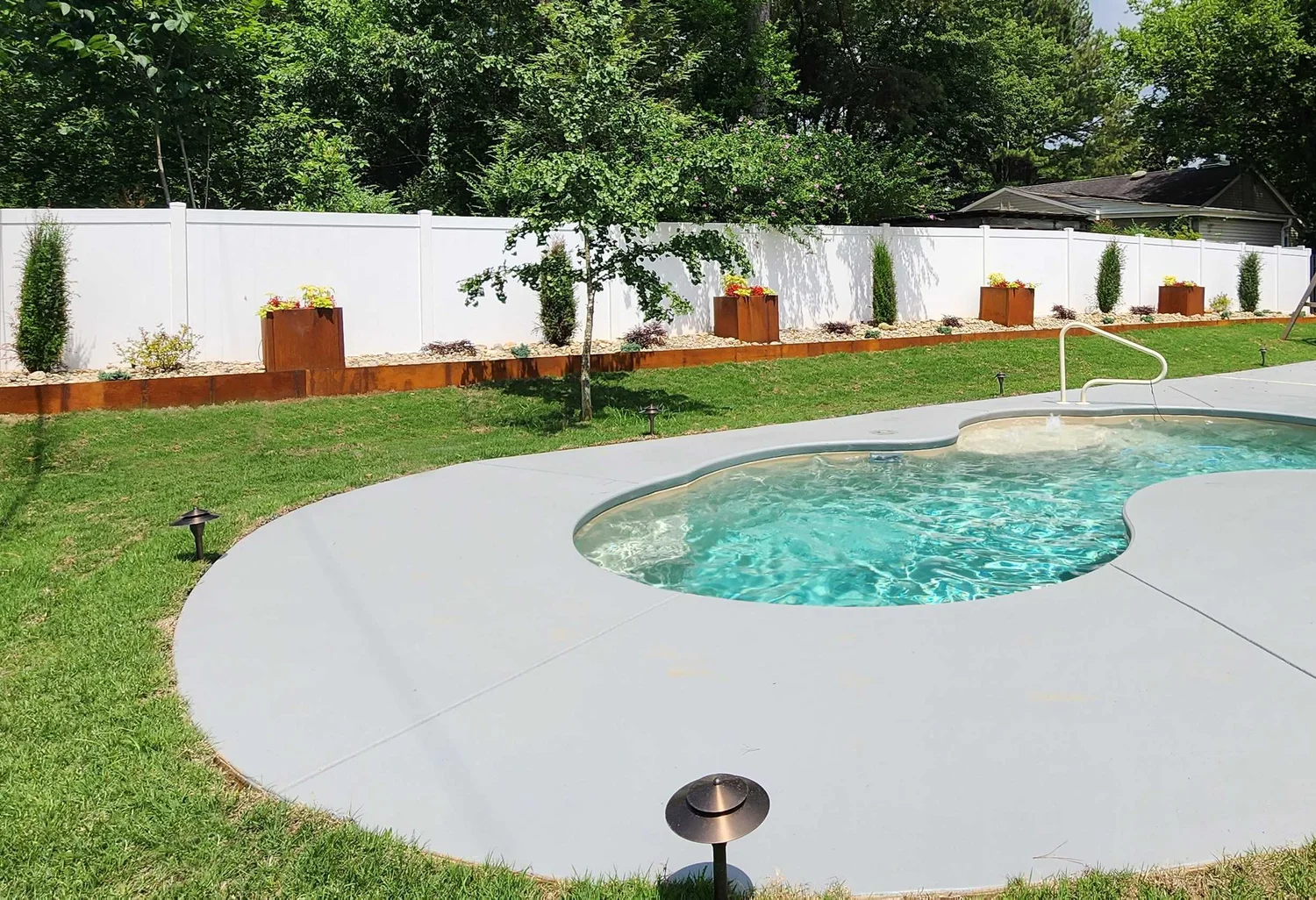 Backyard pool with greenery and fence.