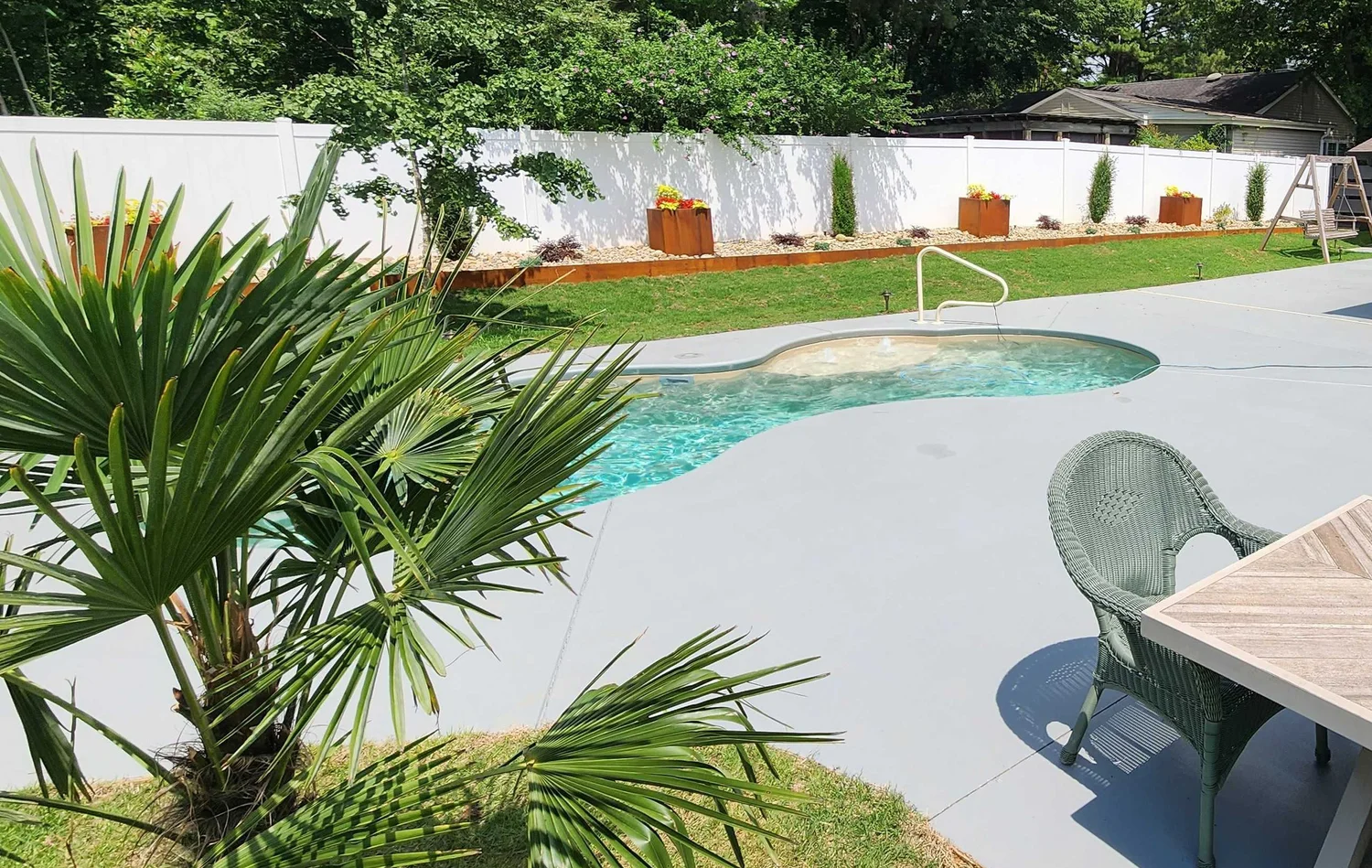 Backyard pool with palms and patio chair