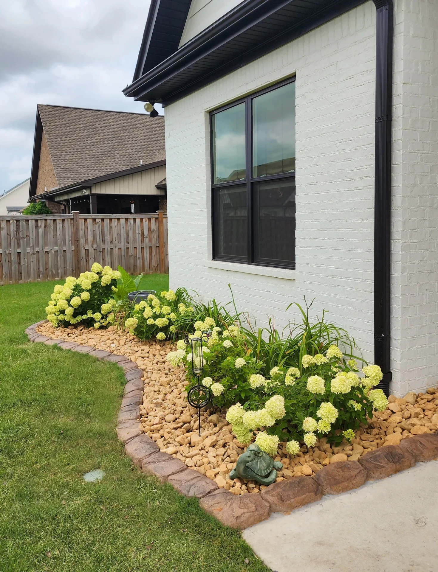 Flower bed with rocks by house.