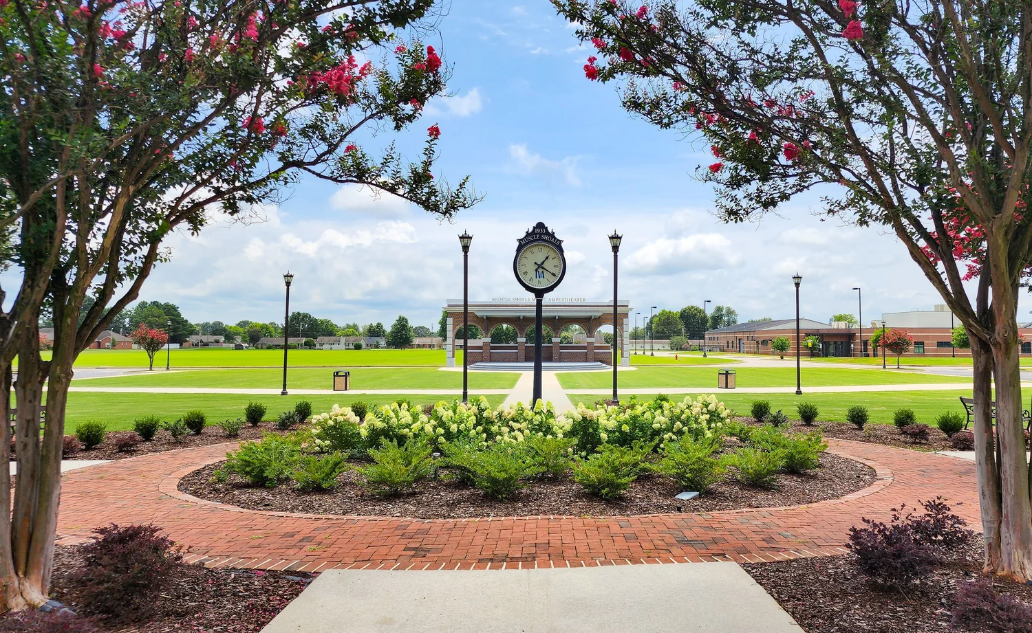 Clock tower in landscaped park with archway.