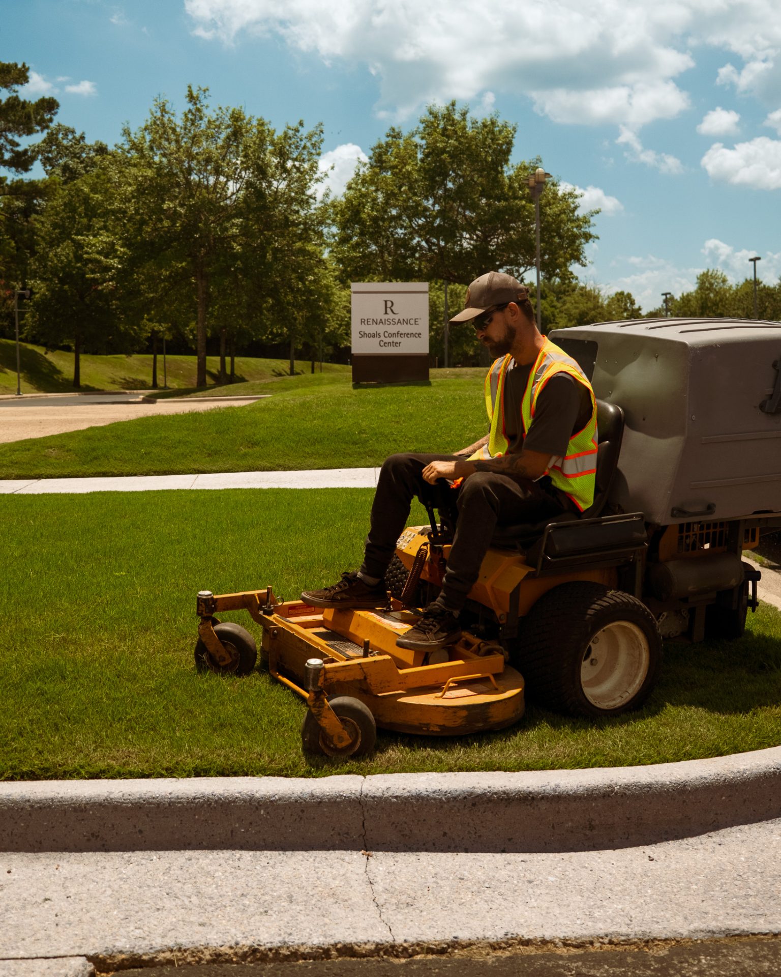 Man mowing lawn near conference center sign