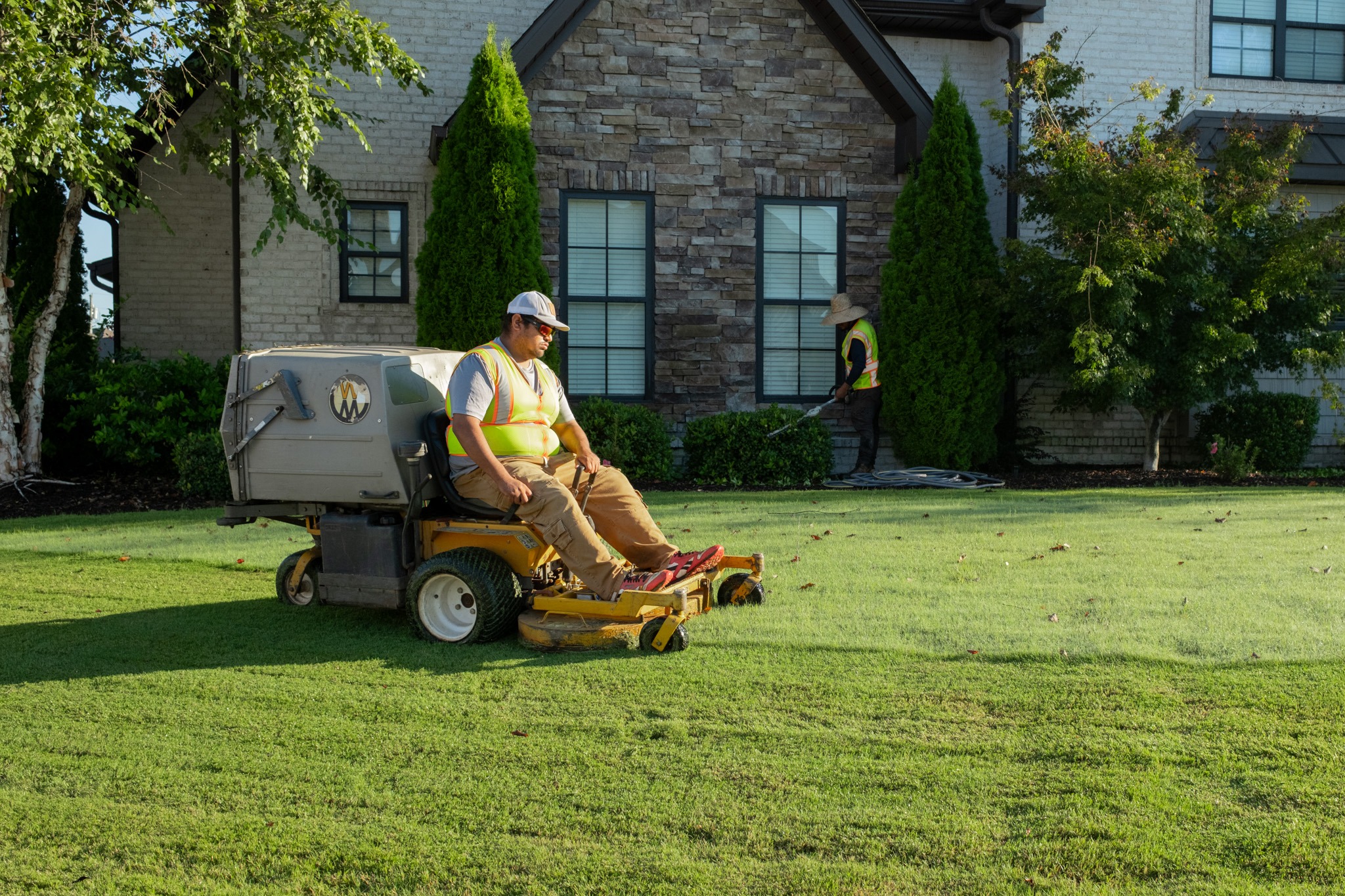 Landscapers mowing lawn and trimming bushes