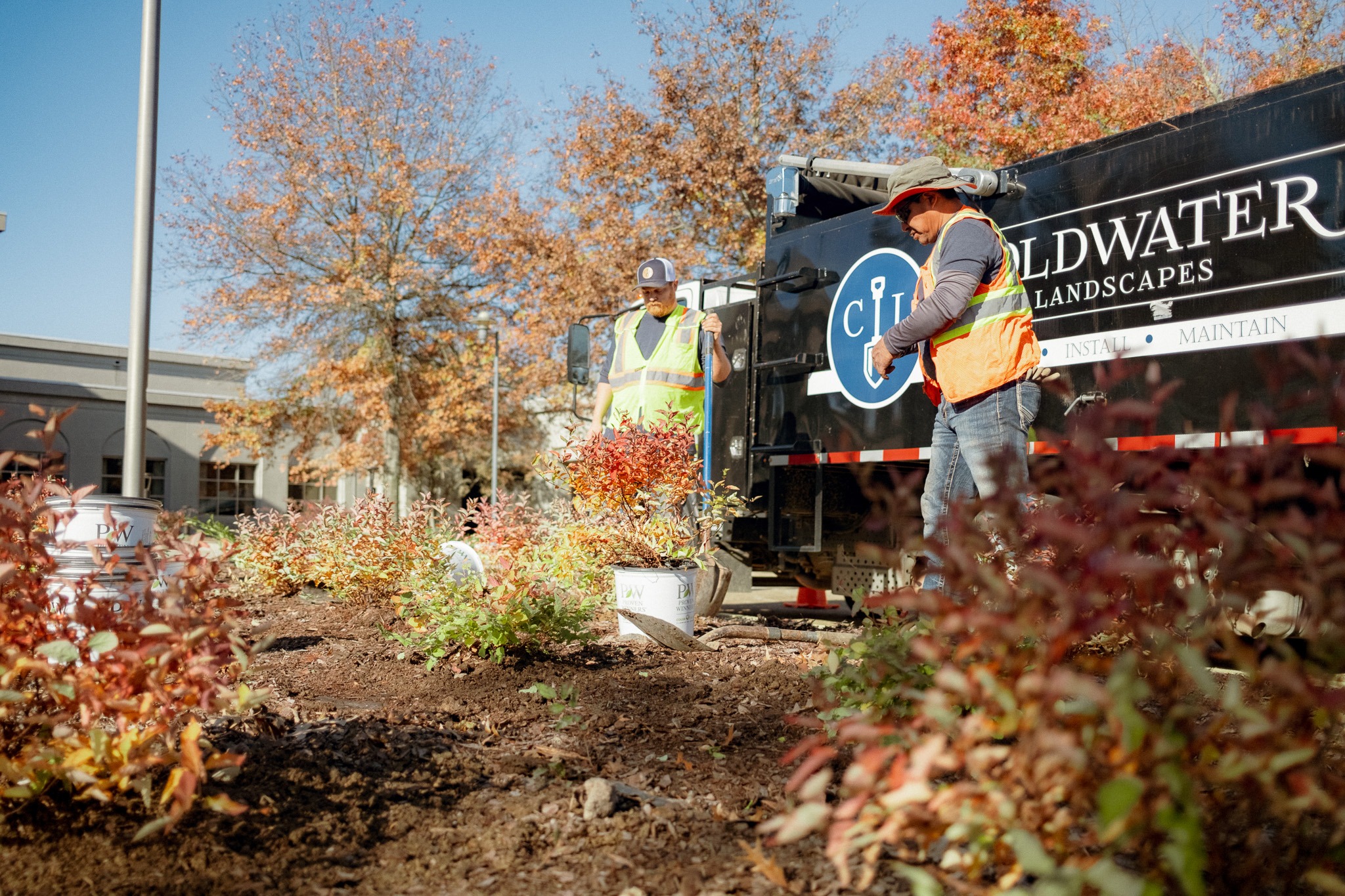 Two workers landscaping among autumn trees