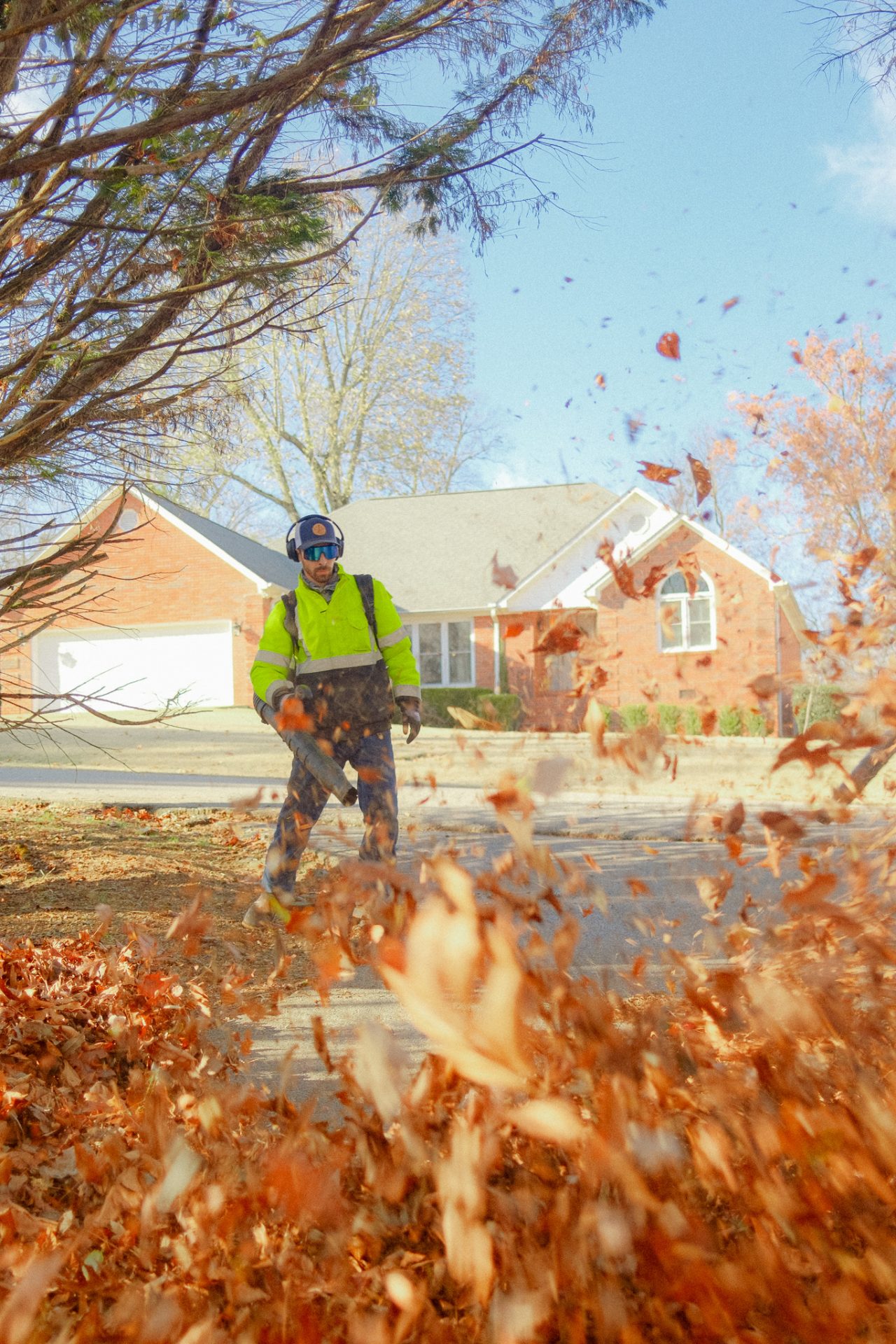Worker blowing leaves on suburban street