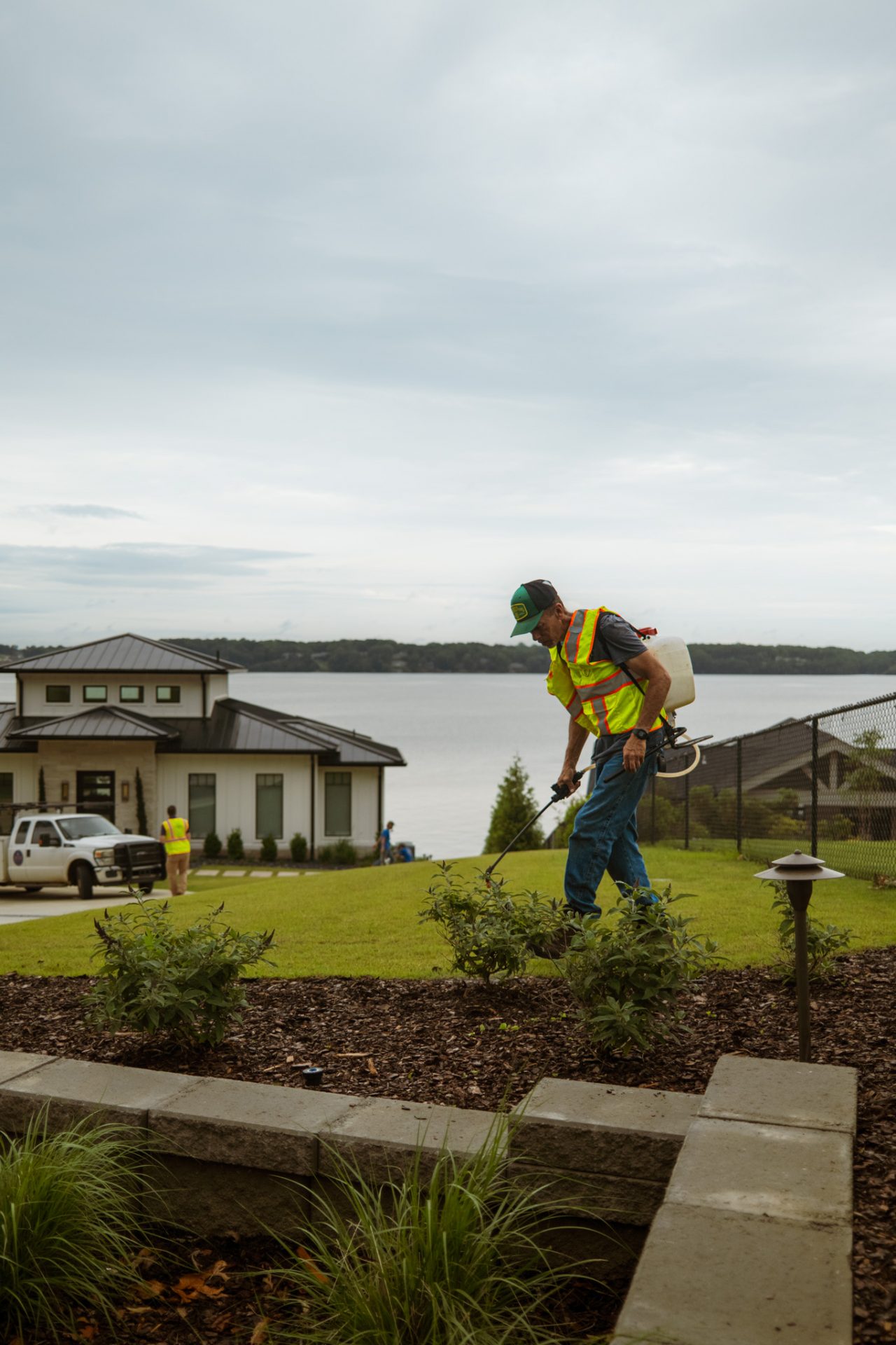 Worker maintaining garden near lake view house